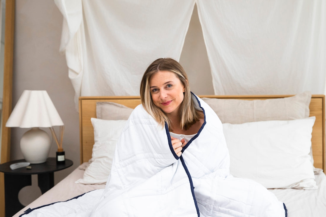 a woman sitting on a bed wrapped in a blanket