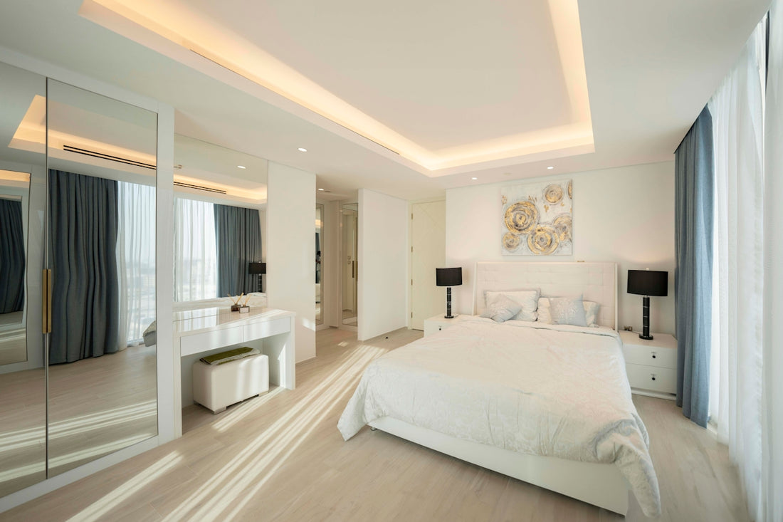 A bedroom with a large white bed sitting next to a window