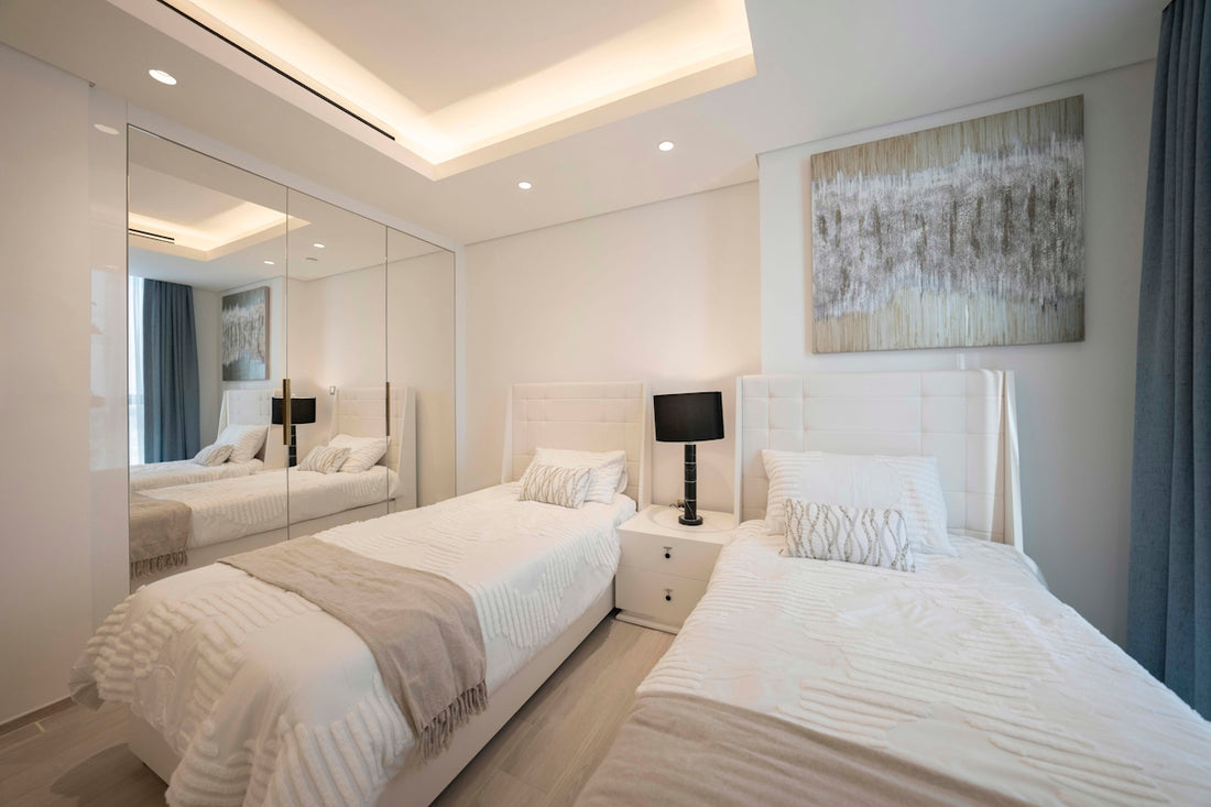 A bedroom with two beds and a mirror