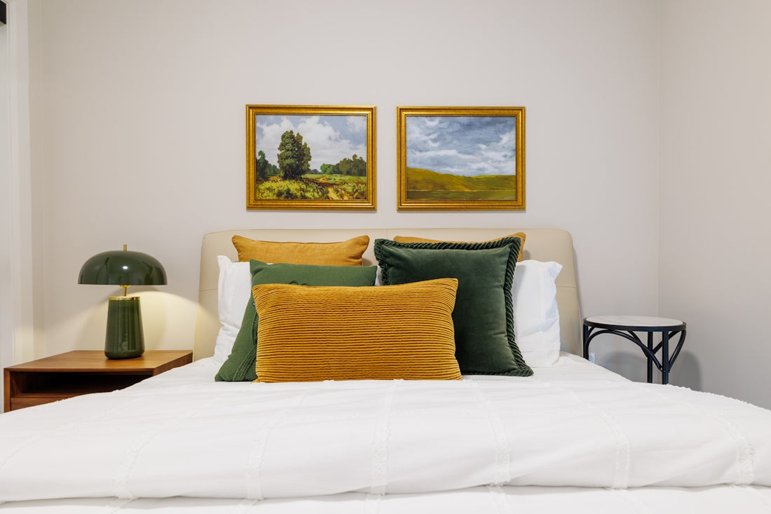 Bedroom with landscape paintings and green lamp.