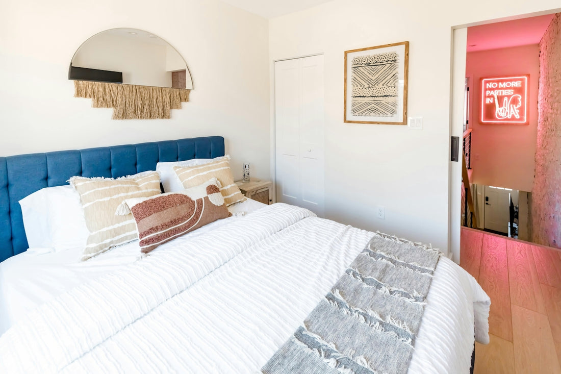 A cozy bedroom with a blue headboard and decorative mirror.